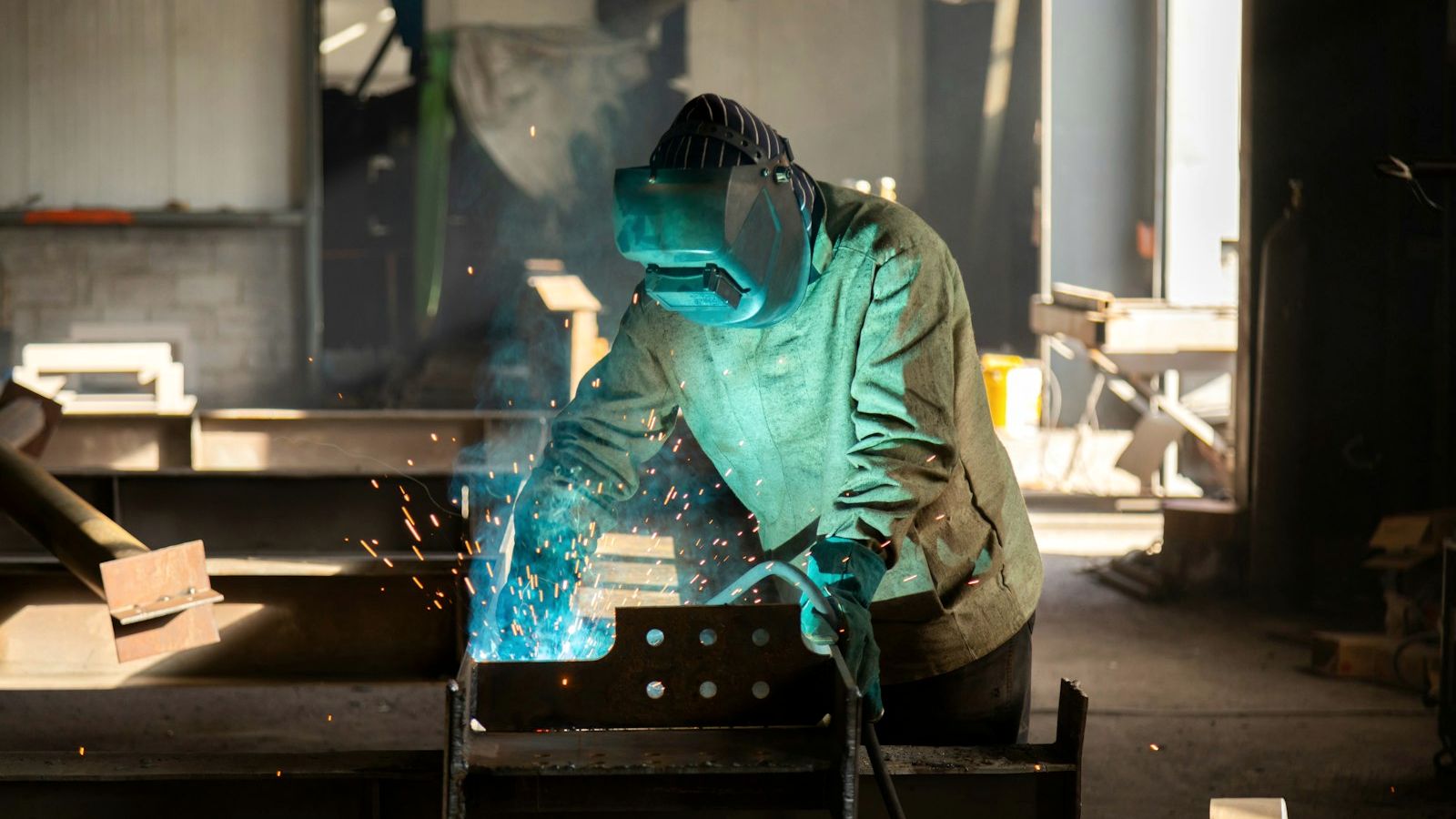 Schweißer bei der Arbeit an einem Stahlbauteil in einer Werkhalle (Beispielbild)