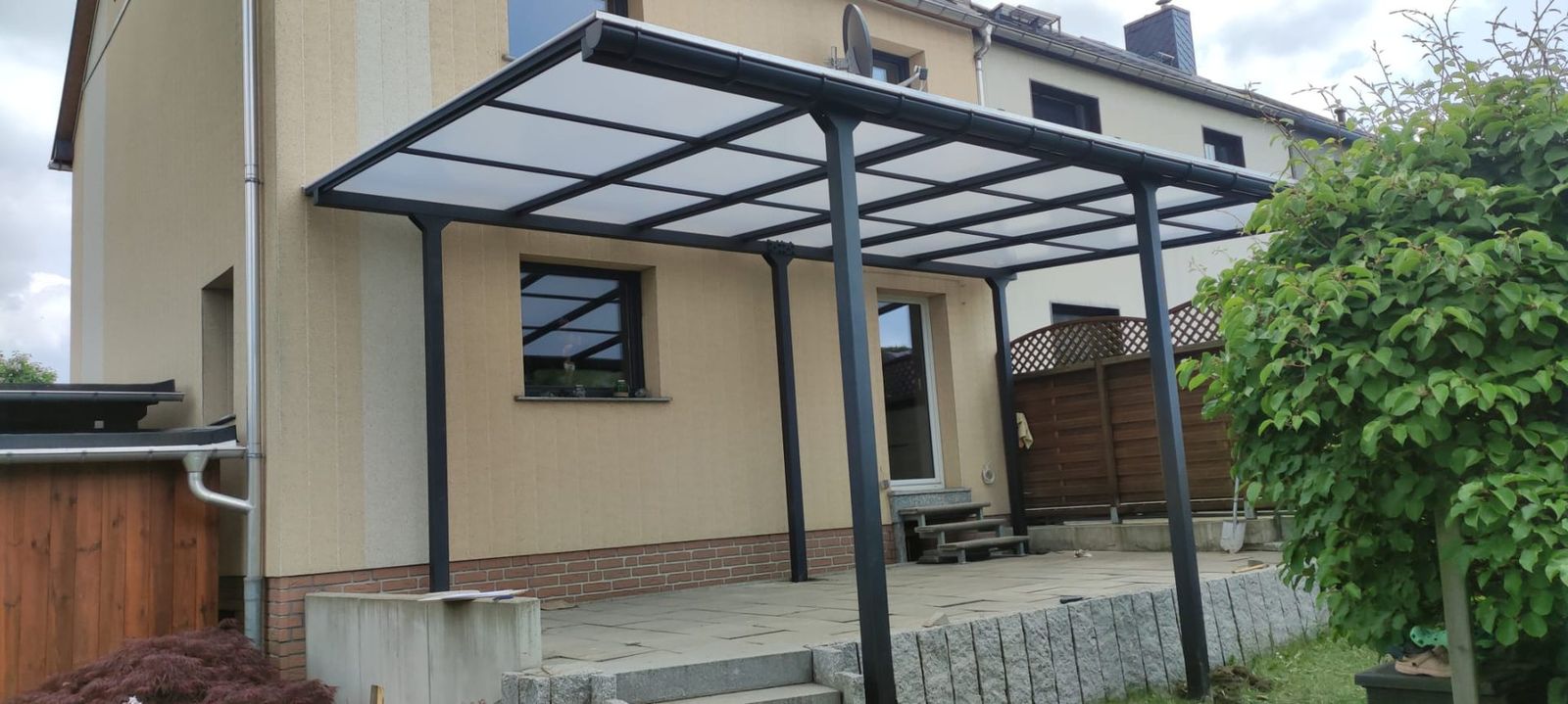 Terrassenüberdachung aus Stahl mit lichtdurchlässiger Eindeckung an einem Wohnhaus